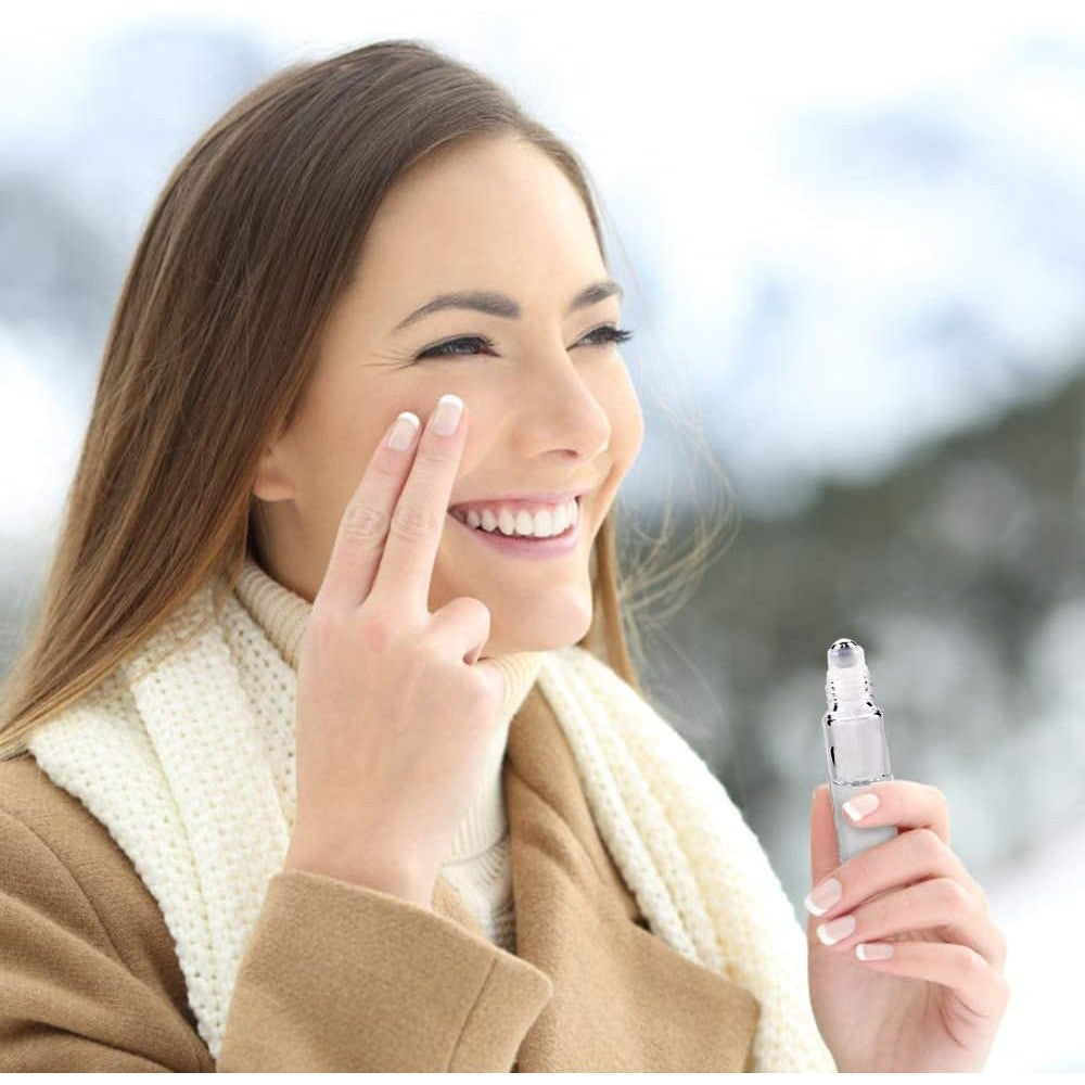 Beautiful woman applies essential oils with roller bottle outdoors. Order our 12-pack roller bottles online today!