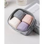 Four silicone travel containers in gray, pink, white, and lavender, neatly packed in a clear zippered pouch.