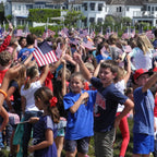Small American Flags on Stick being enthusiastically waved by children at an outdoor event. 100% Authentic, available at Curat Cart in India.