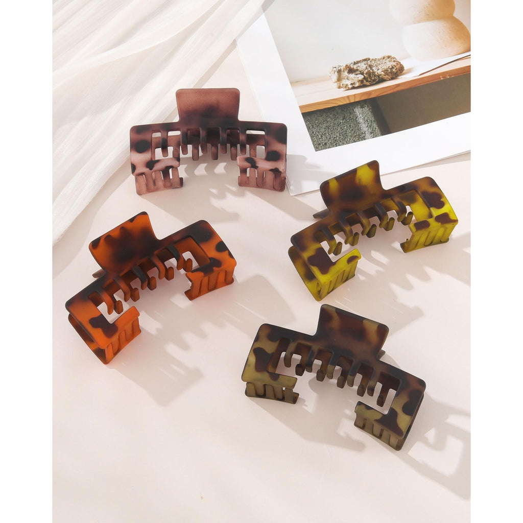 Set of four claw clips in tortoiseshell patterns designed to hold hair under baseball caps. Perfect for a chic, sporty look.