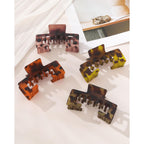 Set of four claw clips in tortoiseshell patterns designed to hold hair under baseball caps. Perfect for a chic, sporty look.