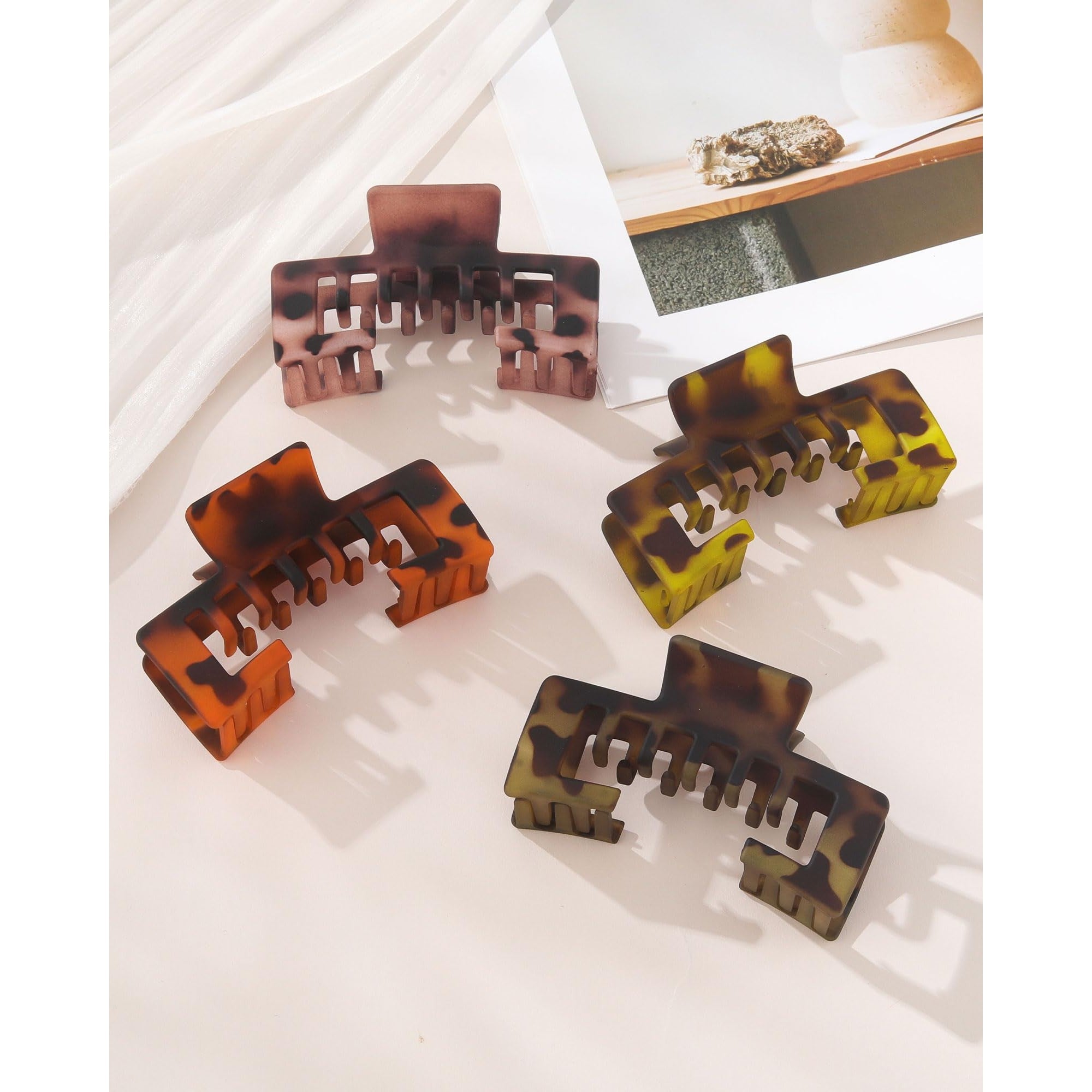 Set of four claw clips in tortoiseshell patterns designed to hold hair under baseball caps. Perfect for a chic, sporty look.