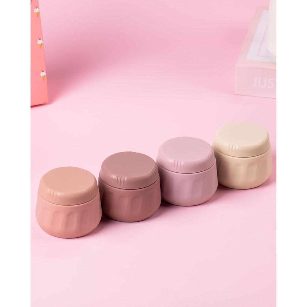 Four pastel-colored travel containers for toiletries, featuring secure lids and a stylish design, perfect for on-the-go use.