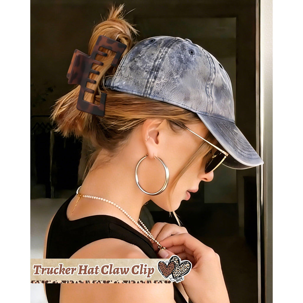 A woman wearing a baseball cap with a trendy claw clip holds her hair up, showcasing a chic, casual style.