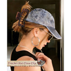 A woman wearing a baseball cap with a trendy claw clip holds her hair up, showcasing a chic, casual style.
