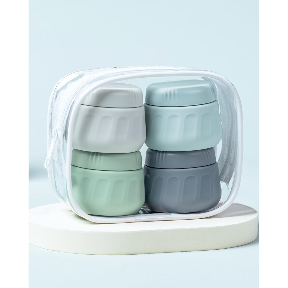 Four stackable travel containers for toiletries in a clear zip bag, ideal for organized packing. Verified by CuratCart.