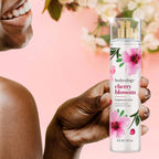A woman smiles while holding Bodycology Cherry Blossom Fragrance Mist. Enjoy a floral scent with notes of cherry blossom and cedarwood. Verified by CuratCart.