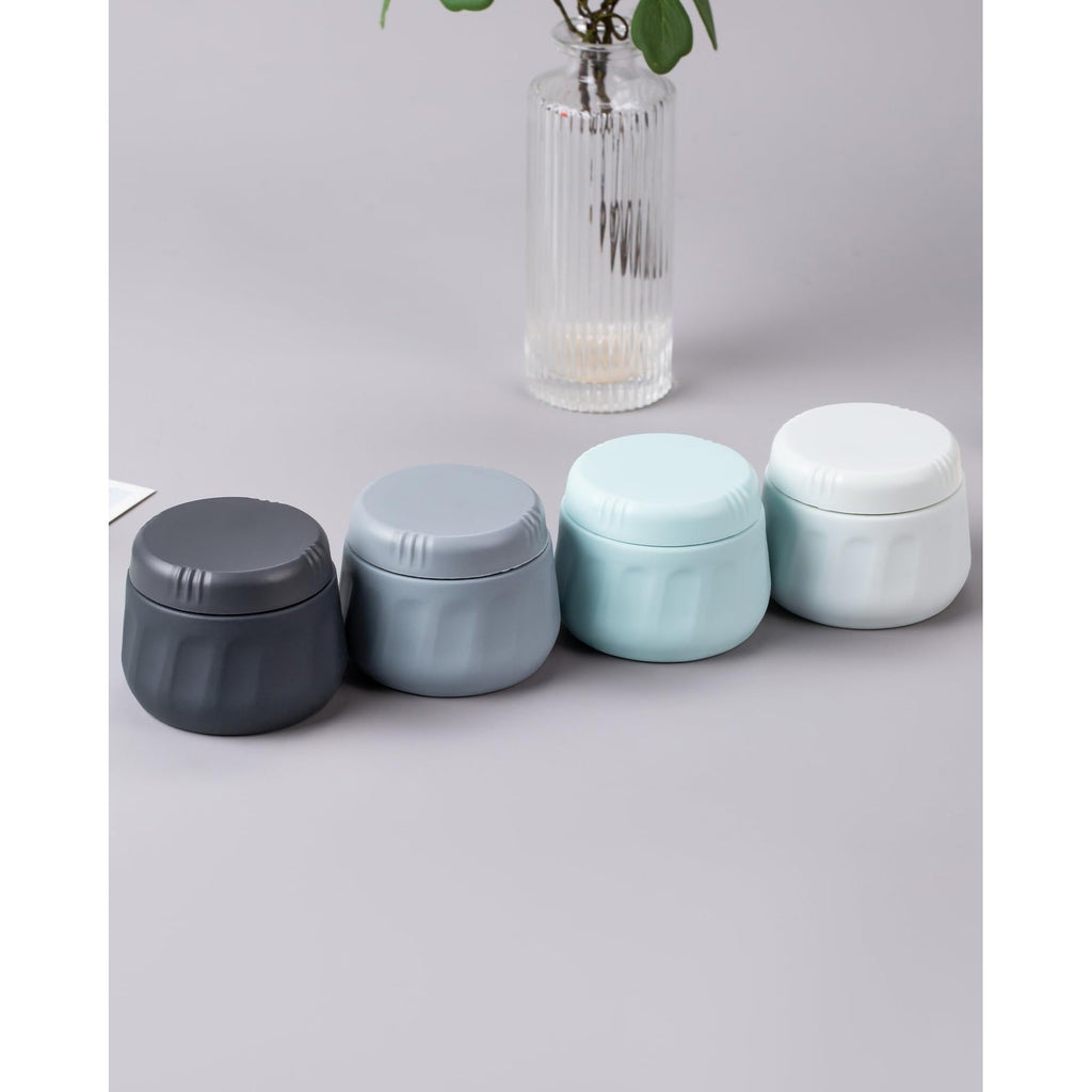 Set of four travel containers for toiletries in gray, light blue, and white. Available online for order, perfect for your travel needs.