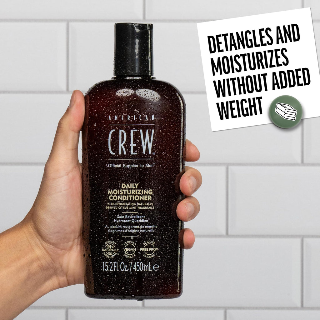 Hand holding a bottle of American Crew Daily Moisturizing Conditioner, designed for men, offering hydration without weight.