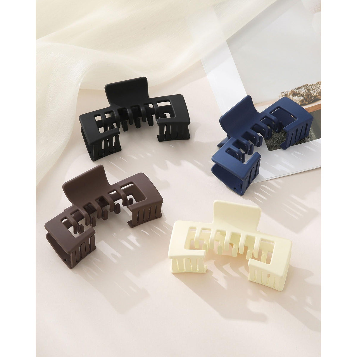 Set of four hat-friendly claw clips in black, navy, brown, and cream. Premium imported for ultimate style and convenience.
