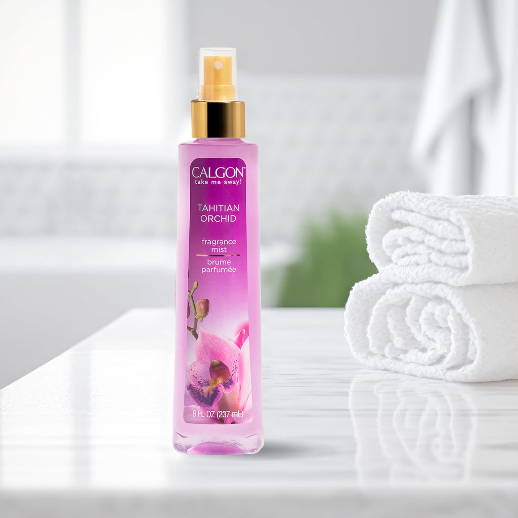 Calgon Tahitian Orchid Fragrance Body Mist displayed on a marble countertop, alongside fresh white towels. Verified by CuratCart.