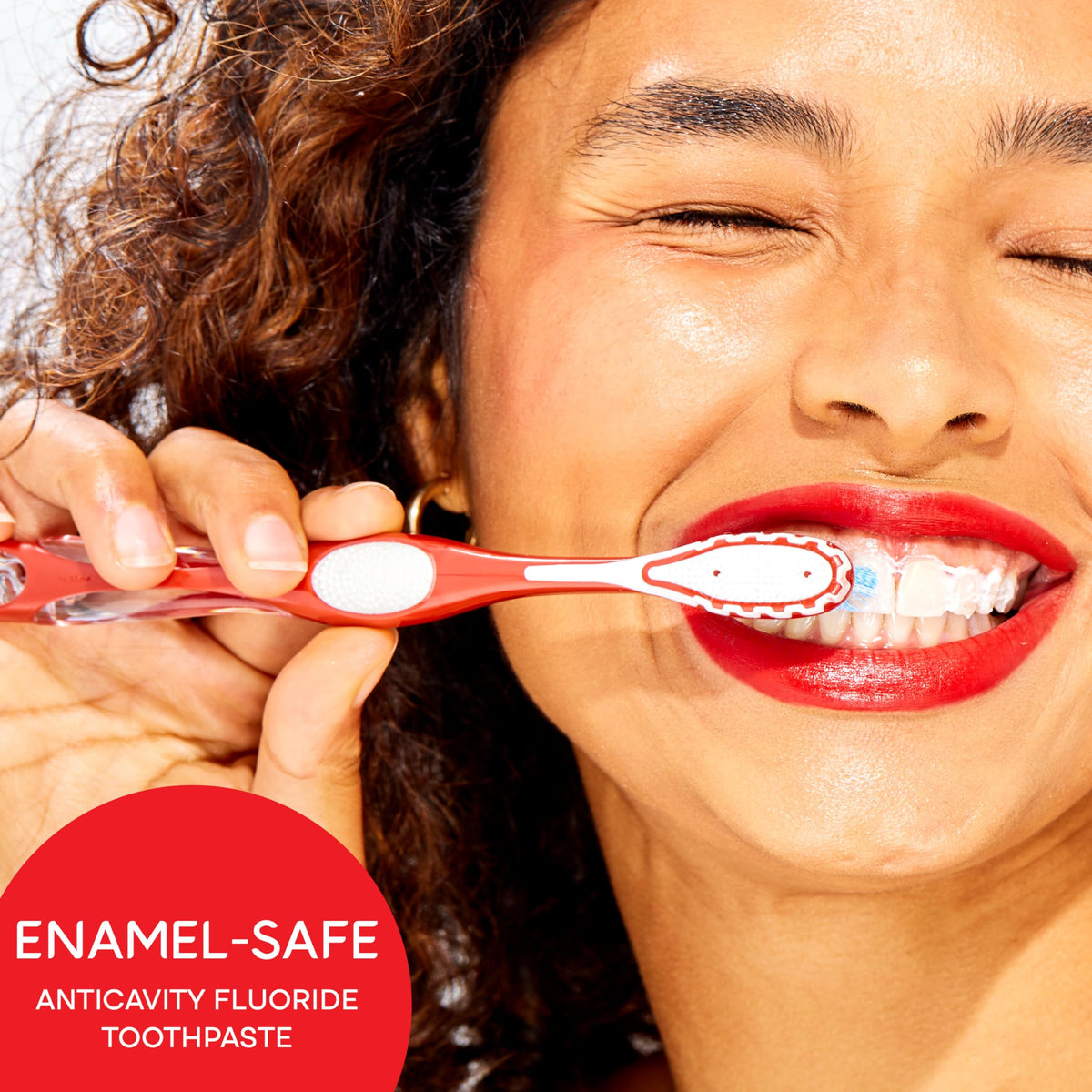 A smiling woman brushes her teeth with Colgate Optic White Toothpaste, showcasing its enamel-safe formula for bright smiles.