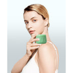 A woman holds a small green travel container for toiletries, showcasing its sleek design and practicality for on-the-go use.