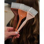 Set of three Framar hair color brushes in varying colors held by a hand, ideal for easy and precise hair coloring.
