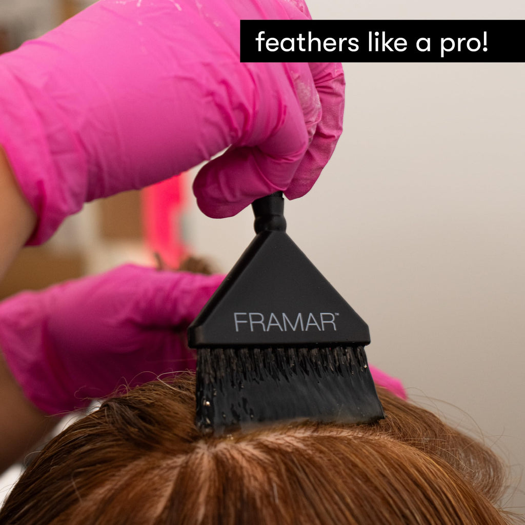 A hand wearing gloves uses a Framar Hair Color Brush on hair, showcasing easy application for vibrant results.