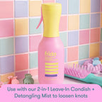Bright pink Frida Kids detangling brush against colorful tiled background. Order online for quick delivery.