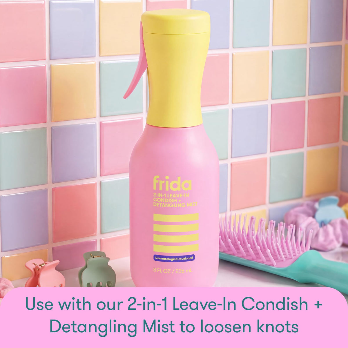 Bright pink Frida Kids detangling brush against colorful tiled background. Order online for quick delivery.