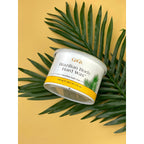 Original GiGi Brazilian Body Hard Wax in a container, placed atop a green palm leaf on a yellow background.