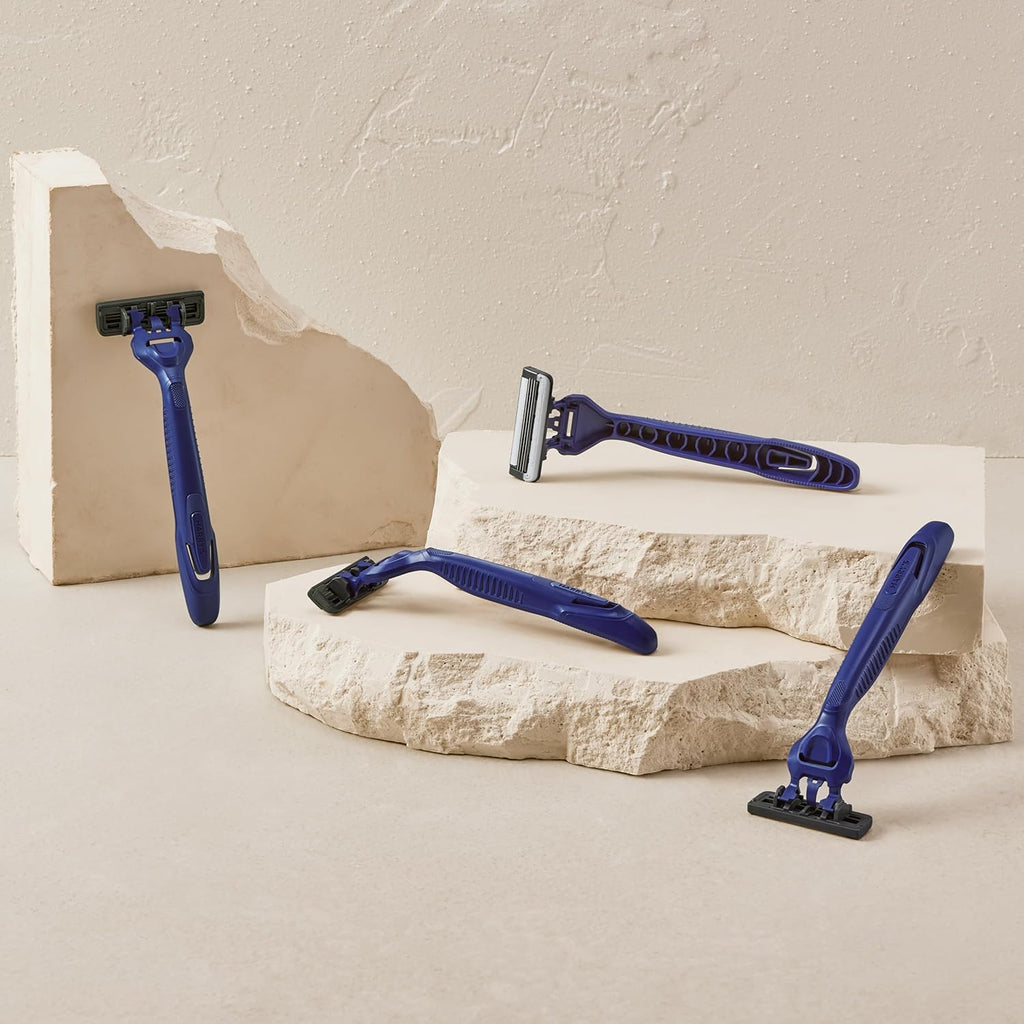Four Harry's disposable razors in sleek blue design displayed on textured stone background. Ideal for smooth shaving.
