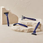 Four Harry's disposable razors in sleek blue design displayed on textured stone background. Ideal for smooth shaving.