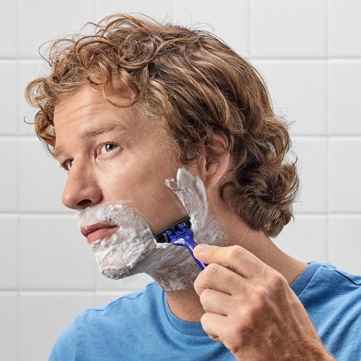 A man using Harry's Disposable Razors for Men in a bathroom setting, showcasing a smooth shave. Verified by CuratCart.