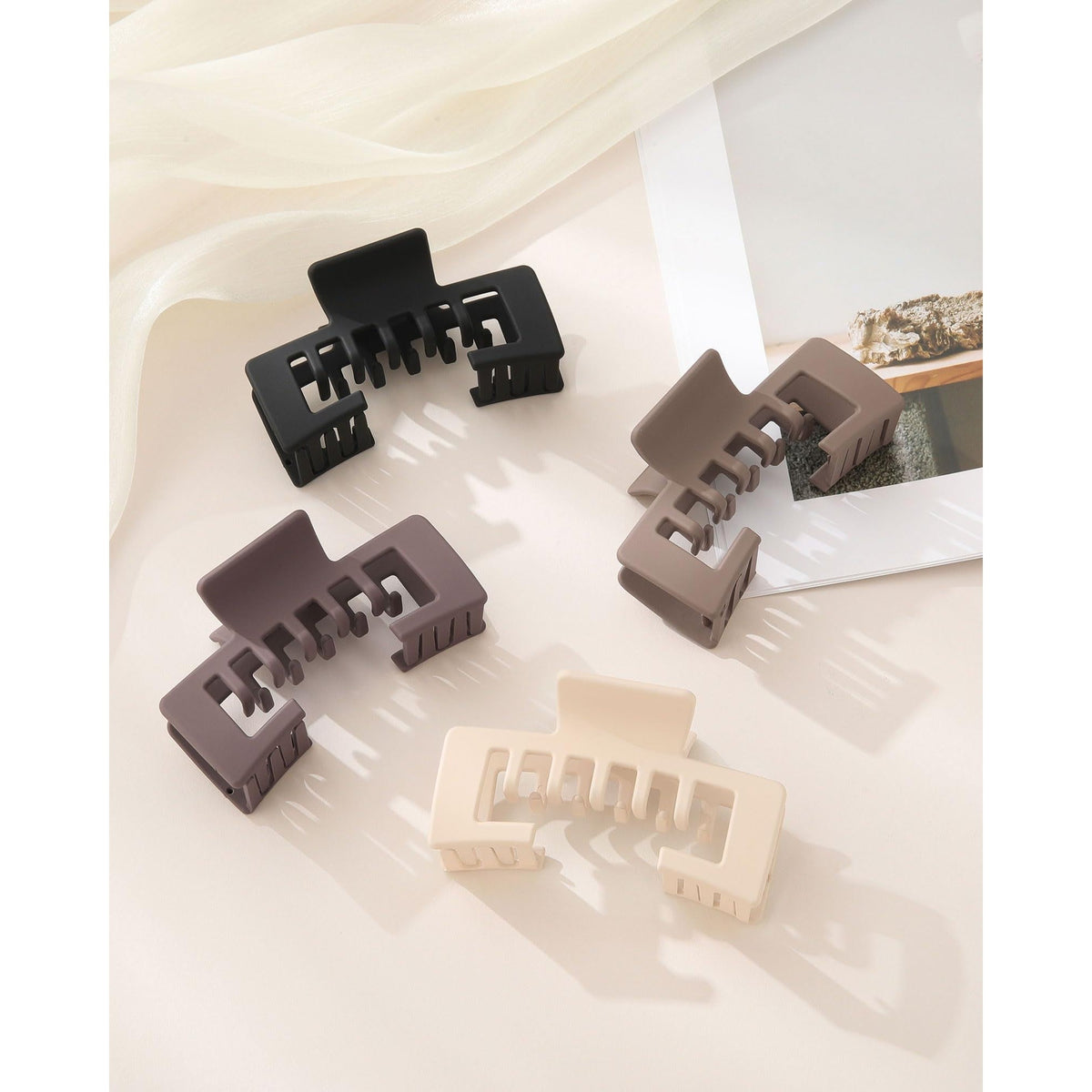 Set of four authentic hat-friendly claw clips in black, brown, beige, and light tan, perfect for styling with baseball caps.