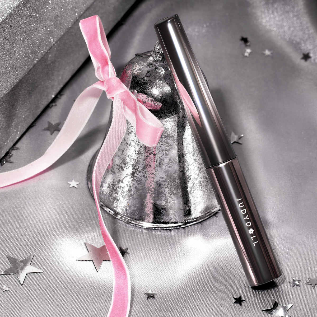 JUDYDOLL Waterproof Mascara-3D Curling T displayed elegantly with a silver bell and pink ribbon. Order online now, available in India.