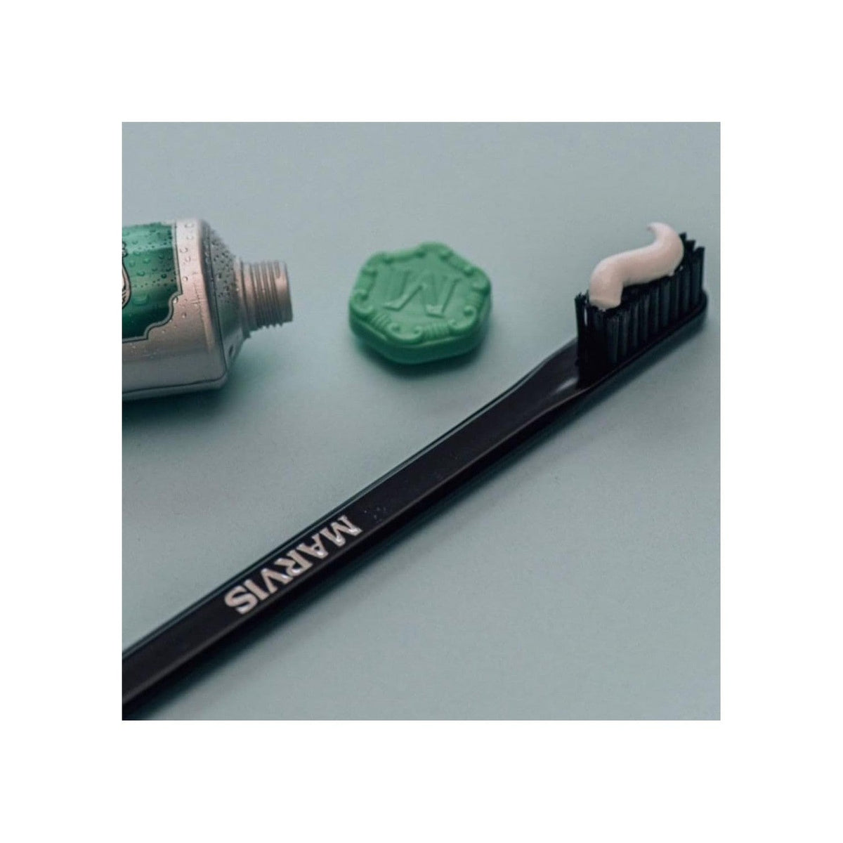 A Marvis toothbrush with a swirl of toothpaste on its bristles, accompanied by a tube of Marvis toothpaste, showcasing authentic branding.