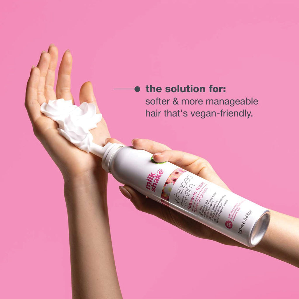 A hand dispensing milk_shake Whipped Cream Leave-In Foam on pink background, promoting soft, manageable hair, vegan-friendly, trusted by CuratCart.