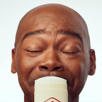 A man with closed eyes smiles while holding an Old Spice antiperspirant stick, showcasing freshness. Verified by CuratCart.