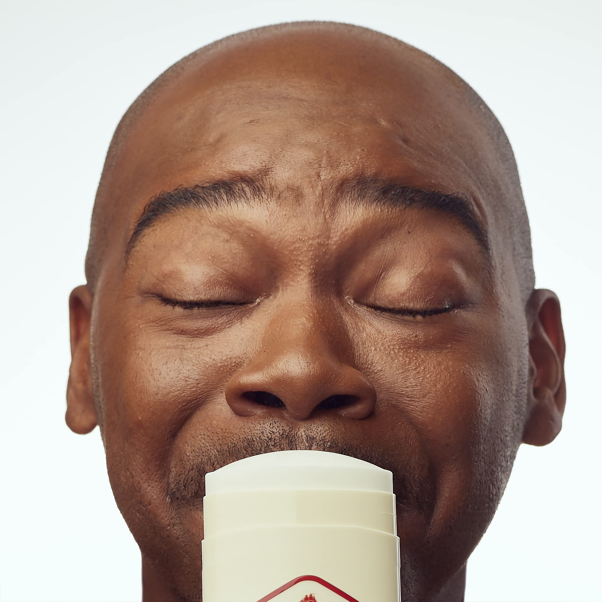 A man with closed eyes smiles while holding an Old Spice antiperspirant stick, showcasing freshness. Verified by CuratCart.