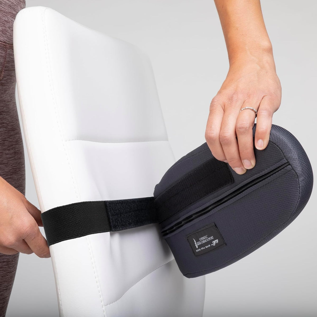 Adjustable McKenzie SuperRoll Lumbar Pillow being secured to a chair. Verified by CuratCart for your comfort.