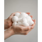 A handful of soft, fluffy Organyc 100% Organic Cotton Balls, showcasing their natural purity and eco-friendly packaging.