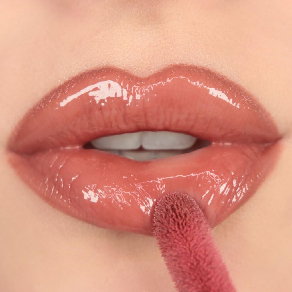 Premium imported Revolution Pout Bomb Plumping Lip Gloss being applied, showcasing a glossy nude finish on lips.