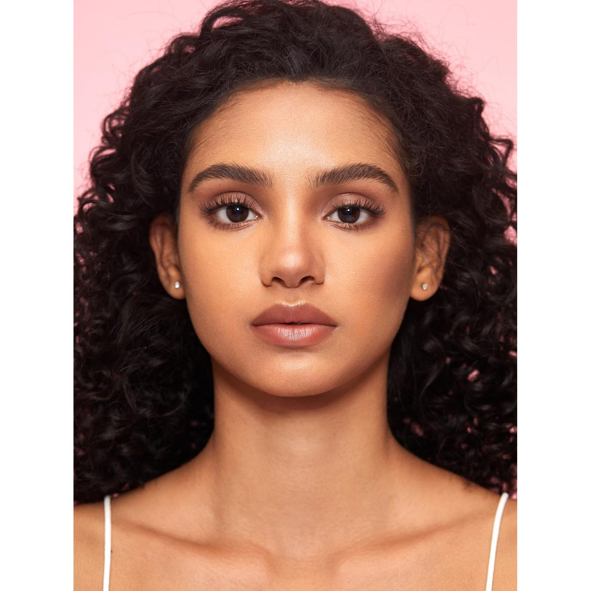A model with curly hair demonstrates the SHEGLAM Fine Line 2-In-1 Nose Contour & features a natural makeup look.