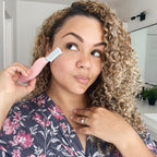 A woman demonstrates the Spa Sciences SIMA Dermaplaning Blade, showcasing its sleek design for effective skin care. Global favorite for smooth skin.