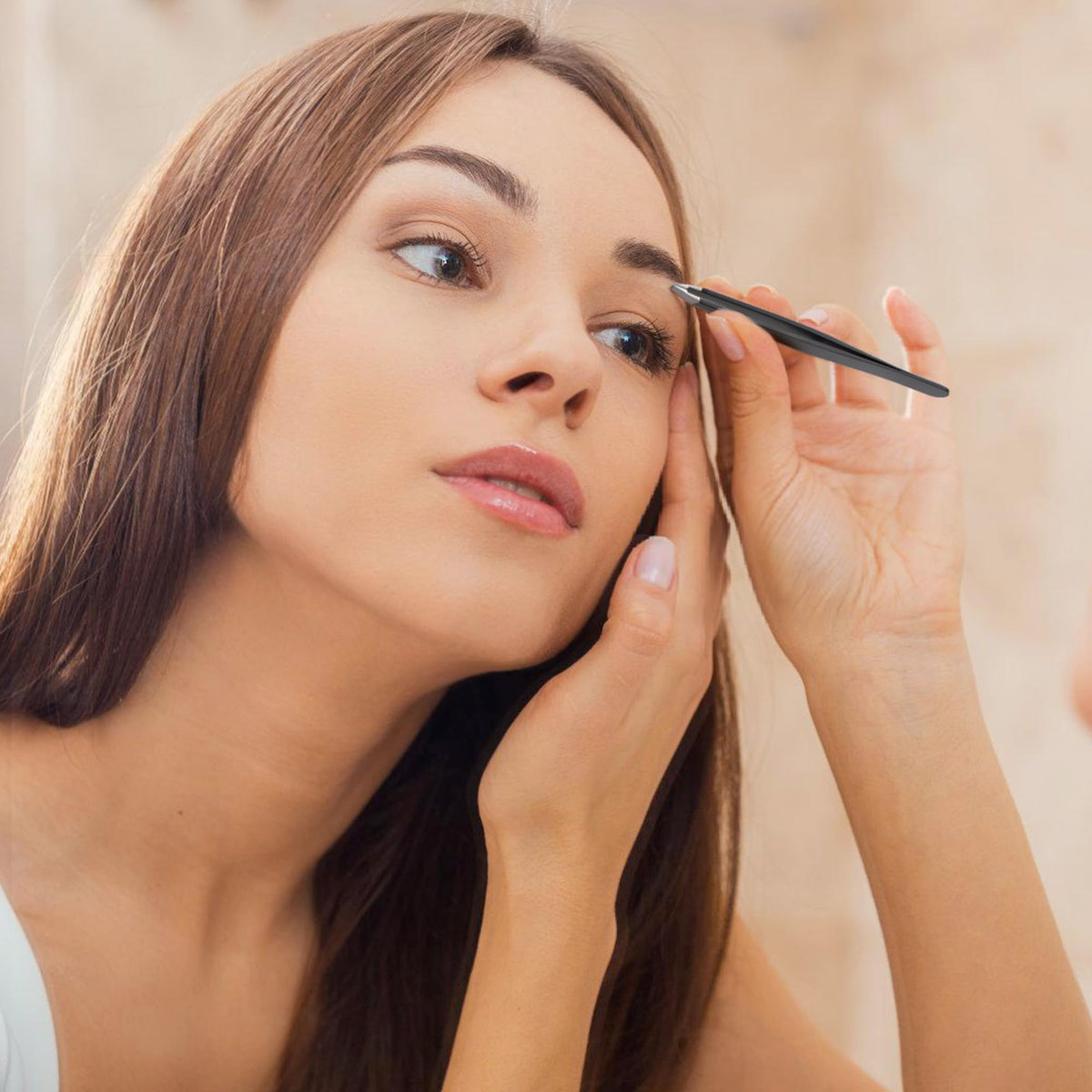 A woman carefully shapes her eyebrows with precision tweezers, trusted by CuratCart for quality grooming tools.