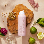VEGAMOUR GRO Dry Shampoo in elegant pink can, surrounded by natural ingredients like minerals and herbs.