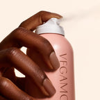 A hand holding VEGAMOUR GRO Dry Shampoo bottle, showcasing its sleek design. Trusted by CuratCart for quality.